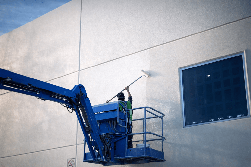 Aplicación de pintura industrial en fachada de nave industrial en Monterrey con plataforma elevadora